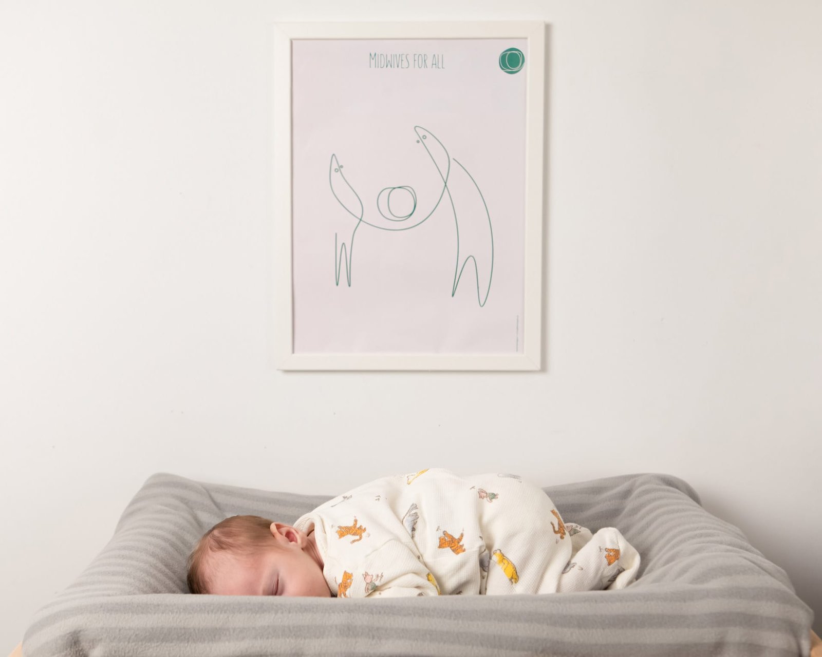 Photograph of a baby sleeping under a framed poster comtaining one of the project's illustrations
